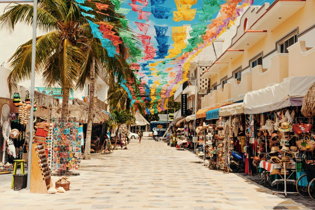 Calle peatonal de Playa del Carmen decorada con papel picado y tiendas de artesanías mexicanas