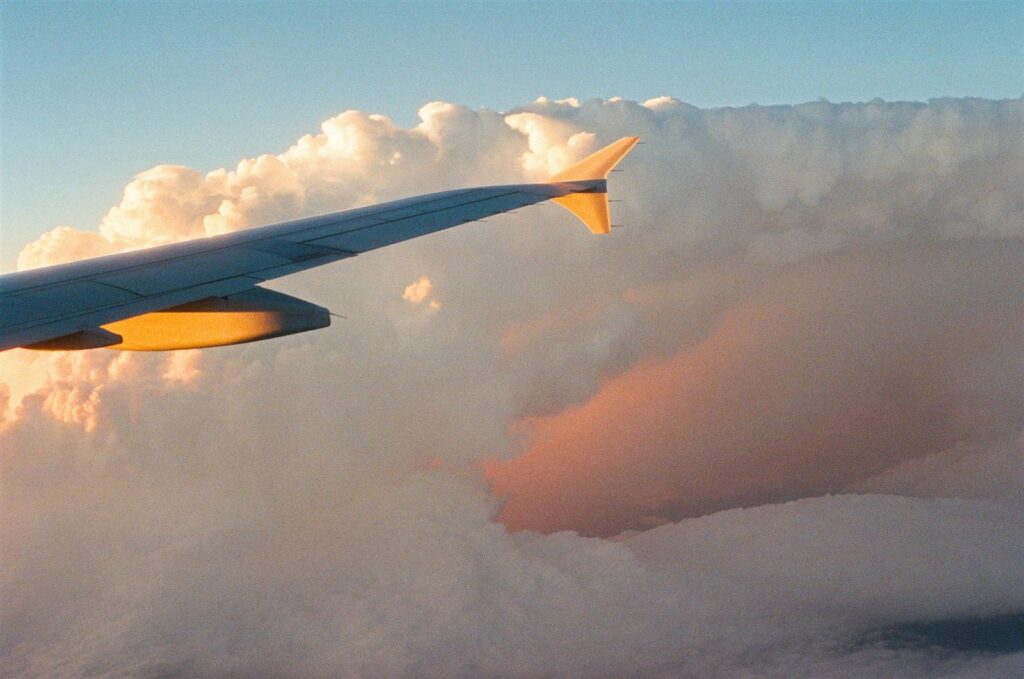 Ala de avión sobre nubes iluminadas por el atardecer durante un vuelo de larga distancia.