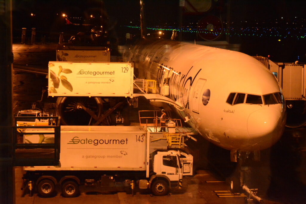 Avión de Qatar Airways en la pista del Aeropuerto de Guarulhos recibiendo servicios en rampa durante la noche.