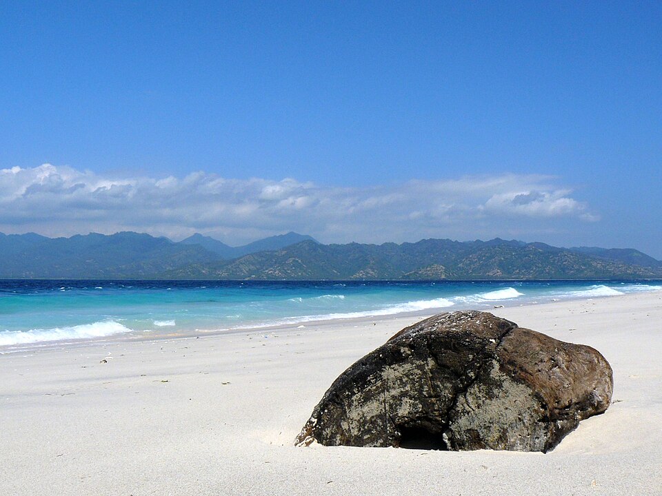 Playa de arena clara en Gili Meno, con el mar y las montañas de Lombok al fondo.
