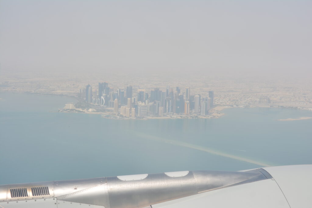 Vista aérea de los rascacielos de Doha y la costa de Qatar tomada desde la ventanilla de un avión.